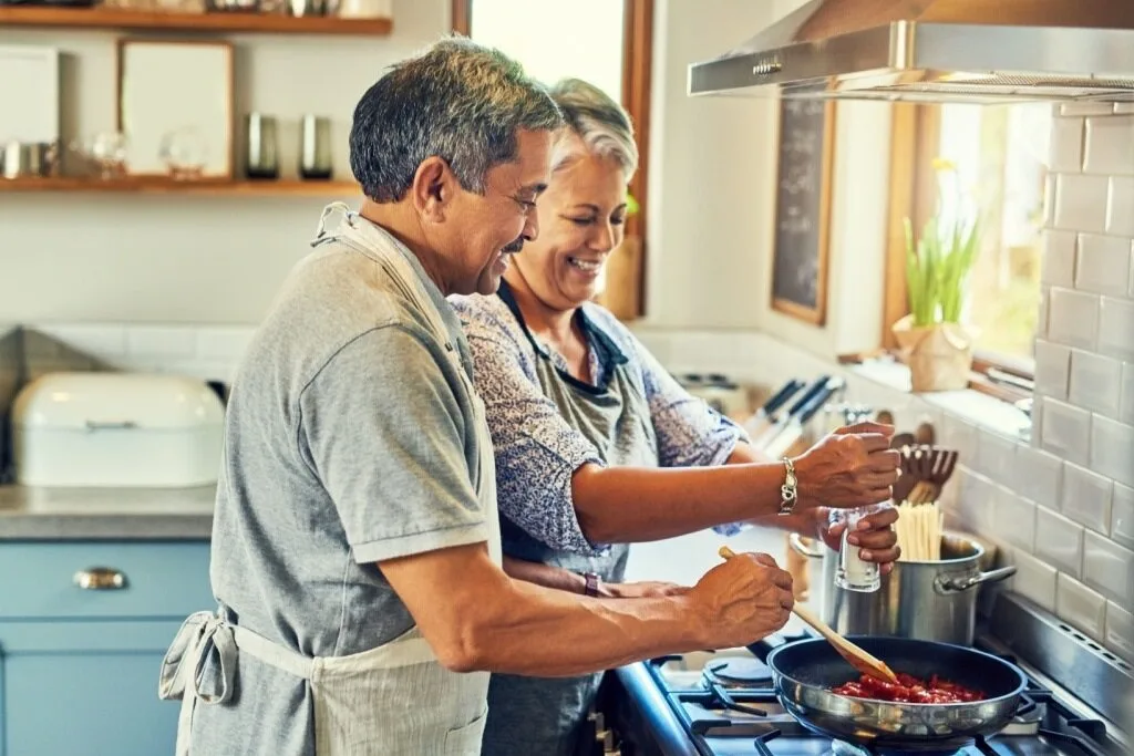 man and woman, presumably husband and wife, cook together in a kitchen